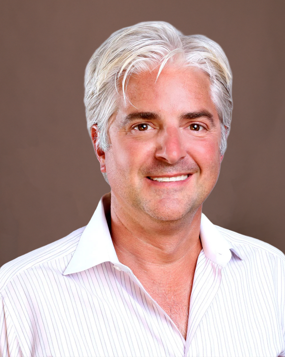 Smiling middle-aged man with silver hair in white collared shirt, professional headshot on plain brown background.