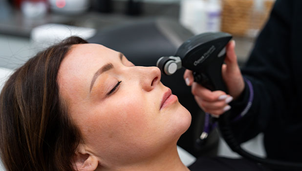 A woman receiving a facial treatment with a handheld device at a spa